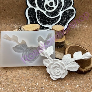 May include: A white silicone mold with a rose design. The mold is shown with a white rose made from polymer clay.