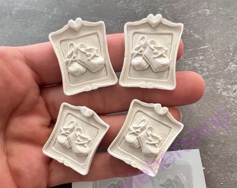May include: Four off-white resin frames, each featuring a pair of ballet slippers. The frames have a heart-shaped top detail. A silicone mold with matching ballet slipper frames is also visible, suggesting a crafting theme.