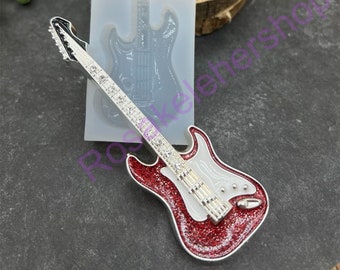 May include: A red and white electric guitar with silver accents and rhinestones. The guitar is made of resin and is a decorative piece. The guitar is next to a clear silicone mold of the same guitar.