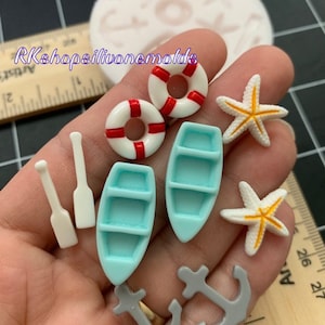 May include: A set of silicone molds for making miniature life preservers, boats, anchors, and starfish. The molds are made of clear silicone and are shown on a hand.