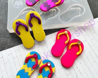 May include: A silicone mold for making flip-flop shaped decorations. The mold has six cavities and is shown with several finished flip-flops in various colors and patterns.