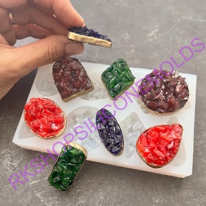 May include: A white silicone mold with eight different shapes for making resin jewelry. The mold is filled with colorful resin pieces in various shapes and colors, including red, green, blue, and purple.