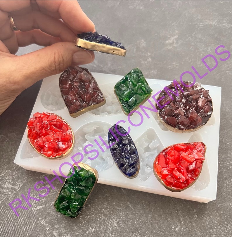 May include: A white silicone mold with eight different shapes for making resin jewelry. The mold is filled with colorful resin pieces in various shapes and colors, including red, green, blue, and purple.