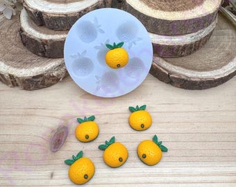 Puede incluir: Un molde de silicona con seis cavidades con forma de naranjas. El molde es blanco y tiene un fondo gris claro. Hay seis pequeños caramelos con forma de naranja al lado del molde.