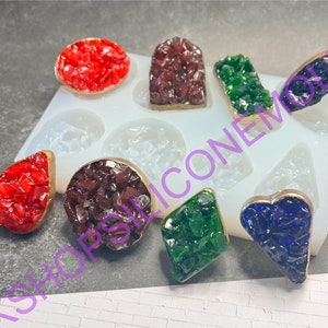 May include: A silicone mold with eight different shapes for making resin jewelry. The mold is filled with colorful resin pieces in red, green, blue, and brown.