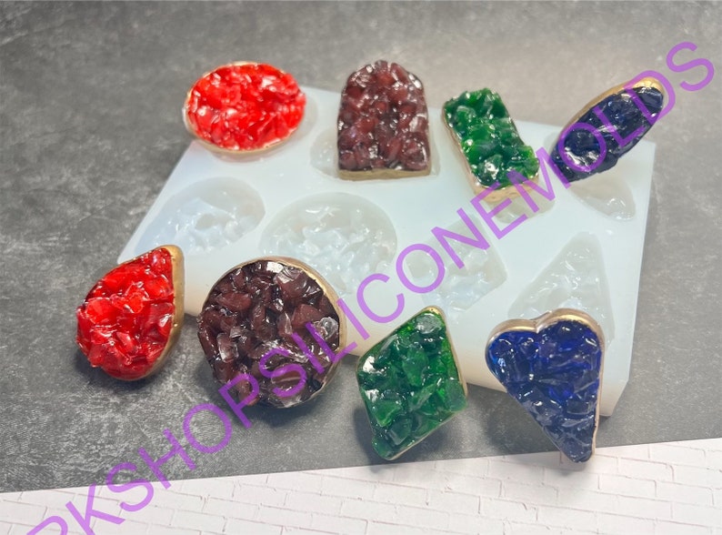 May include: A silicone mold with eight different shapes for making resin jewelry. The mold is filled with colorful resin pieces in red, green, blue, and brown.