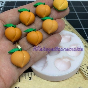May include: A silicone mold for making peach-shaped resin charms. The mold has six cavities and is shown with peach-shaped resin pieces.
