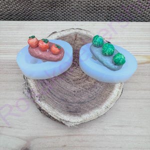May include: Two silicone molds for making miniature food. One mold has three red carrots, the other has three green cabbages.
