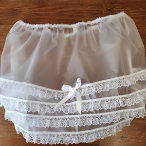 Puede incluir: Enaguas de nylon blanco con tres capas de encaje blanco. La enagua tiene una cintura elástica fruncida.