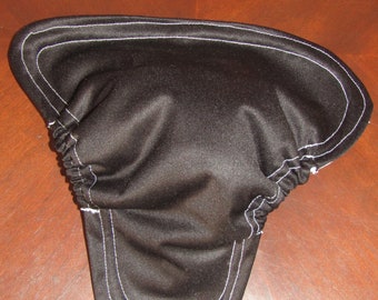 May include: Black fabric item with white stitching along the edges. The item has a curved shape with a gathered section. The stitching creates a defined border around the edges of the fabric.