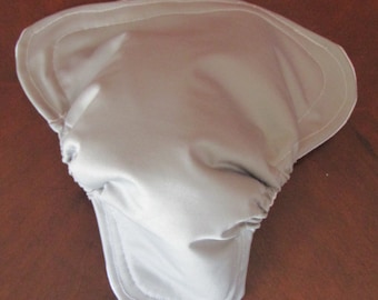 May include: A light gray, cloth diaper cover with a rounded shape and elasticized waist. The cover is made of a soft, smooth material and has a stitched edge. The diaper cover is designed to be worn over a cloth diaper.