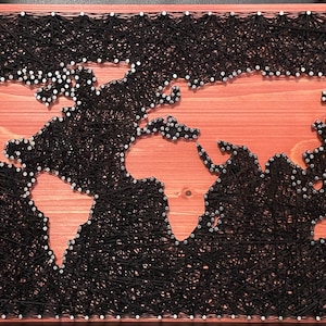 May include: A world map created with string art. Black string is wrapped around nails hammered into a wooden board to create the outline of the continents. The background is a light reddish-brown wood.