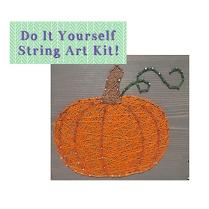 May include: A string art kit featuring a pumpkin design. The pumpkin is orange and has a green stem. The string art is on a wooden background.