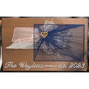 May include: A wooden sign with a string art design of the state of Virginia. The state is divided into two sections, one in pink and white string and the other in blue string. A gold heart is in the center of the design. The sign also has the text "The Waylets - est. 2023" written on it.