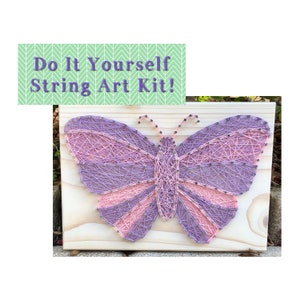 May include: A DIY string art kit featuring a purple and pink butterfly design on a wooden board. The kit includes all the necessary materials to create the artwork, including string, nails, and a wooden base.