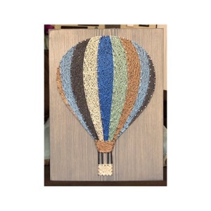 May include: A string art hot air balloon with a brown wooden frame. The balloon is made of blue, green, brown, and beige string.