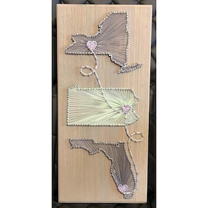 May include: A white ceramic mug with a black handle and the text "But First, Coffee" in a bold, black font. The mug is set against a blurred background, suggesting a cozy setting.