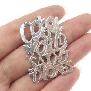 May include: Silver pendant with the words "Cool World Said No More" in a stylized font.