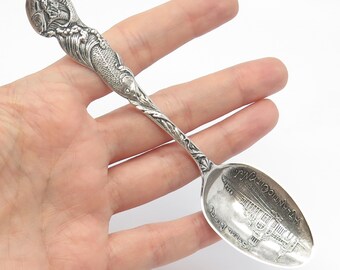 Könnte beinhalten: Sterling-Silber-Souvenirlöffel mit einem detaillierten Bild des "New York Hotels" auf der Schale und einem Fischdesign am Griff.