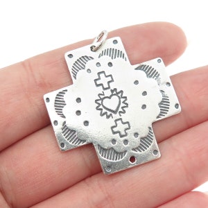 May include: Silver cross pendant with a heart and cross design. The pendant has a detailed, textured surface.