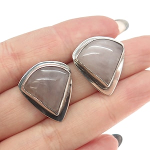 May include: A pair of silver earrings with a light pink gemstone in a triangular shape.