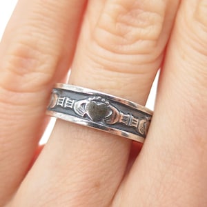 May include: A silver ring featuring a Claddagh design. The ring has a heart at the center, clasped by two hands, and is topped with a crown. The band has a detailed pattern around the heart.