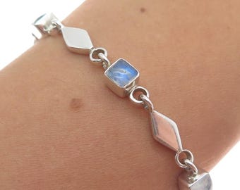May include: A silver bracelet with a delicate chain and square moonstone accents. The bracelet is made of sterling silver and features a polished finish.