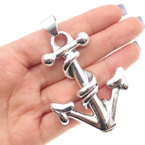 May include: A polished silver anchor pendant with a twisted rope design. The anchor has a classic shape with a loop at the top for a chain. The pendant is a nautical-themed accessory.