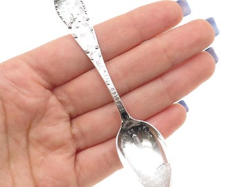 May include: A silver souvenir spoon with an ornate handle and a detailed bowl. The bowl features an engraved image of a building and the words "Bunker Hill" and "Mass". The handle has decorative elements.