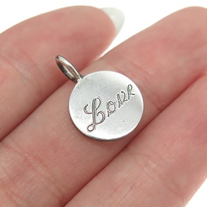 May include: A silver charm with the word "Love" inscribed in cursive script.