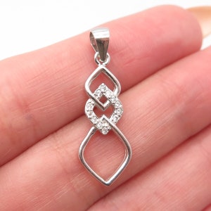 May include: Sterling silver pendant with a clear crystal design. The pendant features two interlocking diamond shapes with a smaller diamond shape in the center.