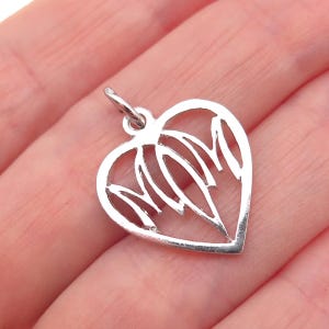 May include: A silver heart-shaped pendant with an openwork design. The pendant features a heart outline with stylized leaf-like shapes inside. The pendant has a small loop at the top for a chain.