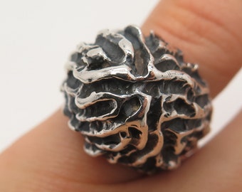 May include: A silver ring with a textured, organic design resembling a brain or a coral formation.