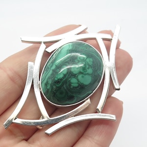May include: A silver brooch with a green malachite stone set in a geometric design.