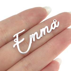 May include: Silver-colored metal pendant with the name "Emma" written in a cursive script.