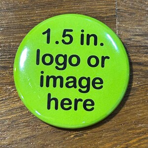 May include: A bright green, round button with the text "1.5 in. logo or image here" in black. The button is approximately 1.5 inches in diameter. The button is on a wooden surface.