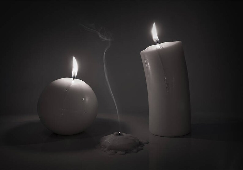 May include: Three white candles, two are lit and one is extinguished with a wisp of smoke rising from the wick.