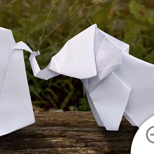 May include: Two white origami elephants standing on a wooden surface. The elephants are facing each other and appear to be interacting.