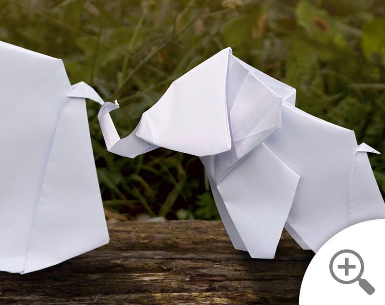 May include: Two white origami elephants standing on a wooden surface. The elephants are facing each other and appear to be interacting.