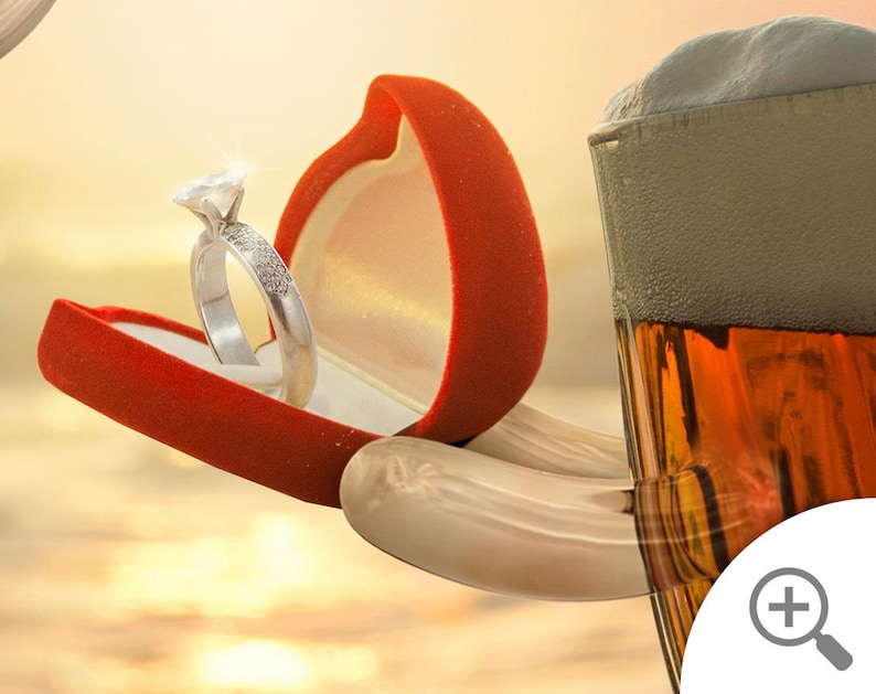 May include: A red velvet ring box with a diamond engagement ring inside, held by a hand reaching towards a glass of beer with a thick head of foam.