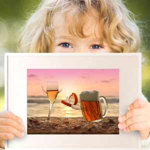 May include: A framed picture of a glass of wine and a beer mug on a beach at sunset. The wine glass has a ring on the rim and the beer mug has a ring on the handle. The ring is in a red box.
