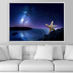 May include: A starfish on a rocky shore under a night sky with a bright Milky Way galaxy and a shooting star.