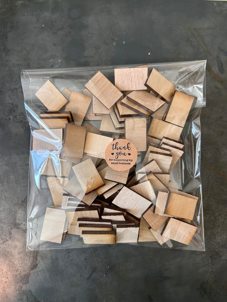 May include: A clear plastic bag filled with numerous small, rectangular wooden pieces with a light brown grain. A circular tan sticker is attached to the front of the bag, featuring the black text, thank you for supporting my small business.