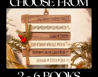 May include: A wooden Christmas ornament with five stacked rectangular pieces. Each piece is engraved with a different message, including "Merry Christmas", names, and hearts. The ornament is decorated with twine and red berries.