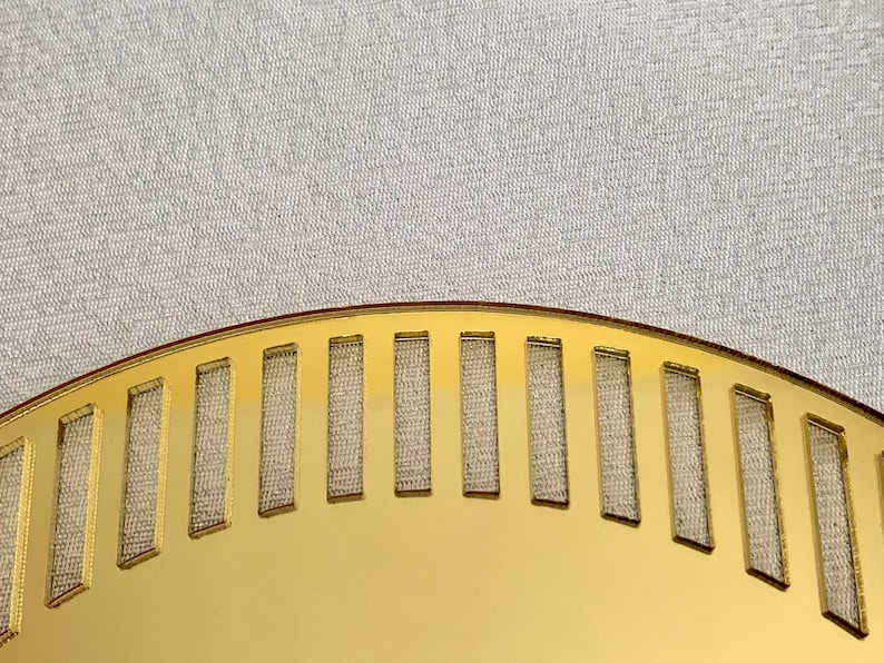 May include: A gold-colored, semi-circular plate with a decorative pattern of evenly spaced rectangular cutouts. The plate has a smooth, shiny surface.