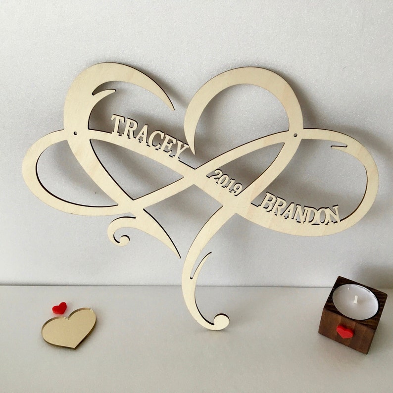 May include: Wooden heart-shaped infinity symbol with the names "Tracey" and "Brandon" and the year "2019" inscribed on it.
