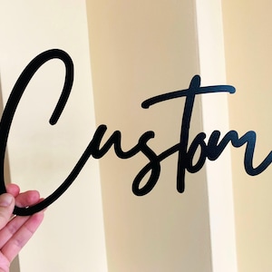 Peut inclure: Une enseigne en métal noir avec le mot "Custom" écrit en cursive.