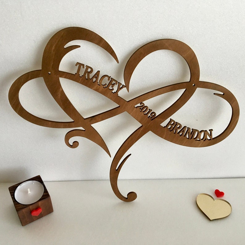 May include: A wooden heart-shaped infinity symbol with the names "Tracey" and "Brandon" and the year "2019" carved into it.