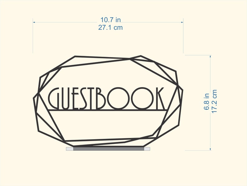 K&ouml;nnte beinhalten: Schwarzer geometrischer Rahmen aus Metall mit dem Wort "GUESTBOOK" in der Mitte. Der Rahmen ist 27,1 cm breit und 17,2 cm hoch.