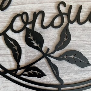 May include: Black metal wall decor with the word "Conserve" in a cursive font, surrounded by stylized leaves.